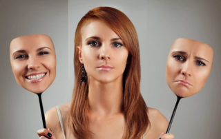 Woman with no facial expression, but holding a sad face image on her right hand and a happy face image on her left hand.