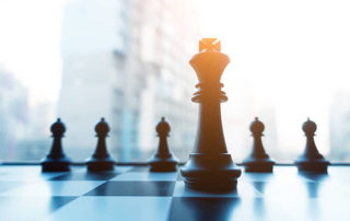 A close up of chess sets with a building in the background.