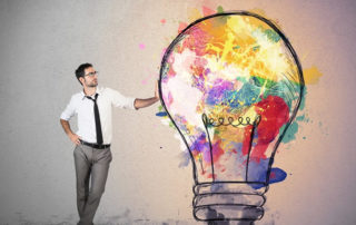 Man standing next to a colourful and creative light bulb drawing.