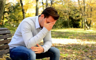 man on bench with hand in the face.