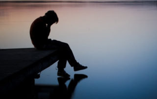 Silhouette of sad person at the river dock