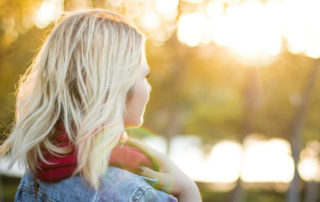 Blonde woman staring and thinking into the garden.