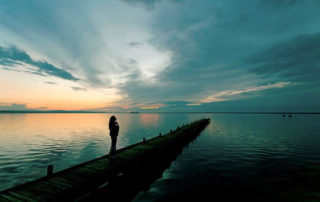 Woman standing on a dock looking out into the ocean.