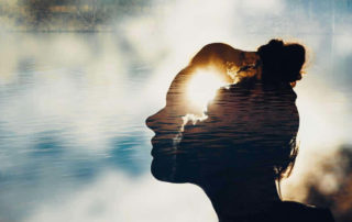 A graphic design illustration of water, sky and silhouette of a woman's face.