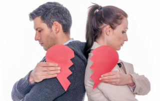 A man and woman with their backs against each other, each holding a broken heart.