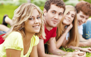 Youth on a grass looking at camera smiling.