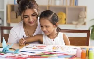 Mother and her child sitting on a table and drawing.