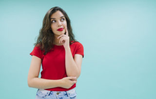 Womain in red t-shirt thinking with arms half folded.