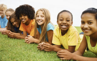 Happy children lying in a row facing the camera.